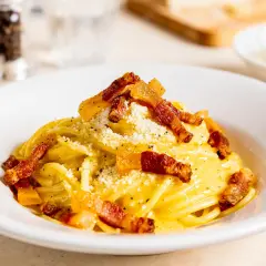 Ein Teller mit authentischer Spaghetti Carbonara, garniert mit knusprigem Guanciale und Pecorino. Ein wahrer Genuss der italienischen Küche.