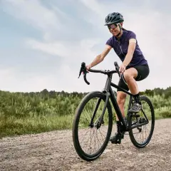 Kobieta na rowerze pokonuje szutrową drogę, ciesząc się jazdą w stylu gravel czy cross.