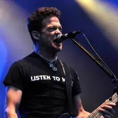 Jason Newsted z zespołu, w czarnej koszulce z napisem "LISTEN TO N", śpiewa do mikrofonu, grając na basie.