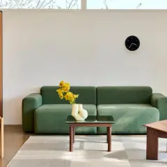 Grünes Sofa, Holzsessel und Beistelltisch im skandinavischen Einrichtungsstil. Ein moderner Wohnbereich mit minimalistischer Ästhetik.