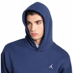 Młody mężczyzna w granatowej bluzie z kapturem Nike Jordan, z małym białym logo Jumpmana na piersi.