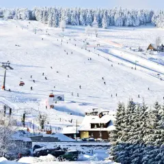 Stok narciarski w Karkonoszach, idealne miejsce na ferie zimowe 2026 dolnośląskie. Narciarze szusują, kolejki wywożą na szczyt.