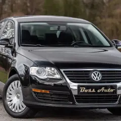 Czarny Volkswagen Passat B6 na tle drzew. Elegancki, lśniący lakier i chromowane detale podkreślają jego klasę.