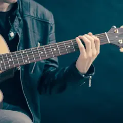 Zwinne palce gitarzysty tworzą akord na gryfie.