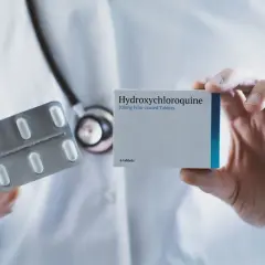 Lekarz prezentuje opakowanie Hydroxychloroquine Adamed i blister z tabletkami.