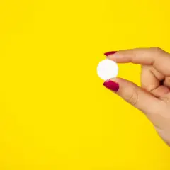 Dłoń trzyma białą tabletkę. Cytrynian magnezu na co? Na stres, zmęczenie, czy lepszy sen.