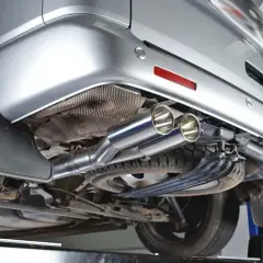 Detalle del sistema de escape de un vehículo plateado. Consulta el precio de limpieza del filtro de partículas.