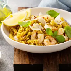 Pyszny makaron z ciecierzycy z krewetkami, cytryną i parmezanem, udekorowany bazylią.