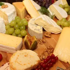 Un ricco assortimento di formaggi tipi, con uva, fichi, noci e fragole, perfetto per un aperitivo gourmet.