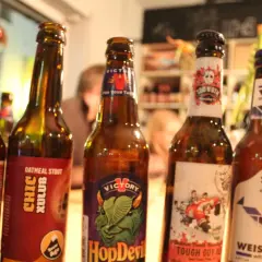 Fünf Flaschen Craft Beer stehen nebeneinander. Jede Flasche hat ein einzigartiges Etikett, das die Vielfalt von Craft Beer zeigt.