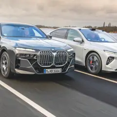 Dwa nowoczesne sedany, w tym chińskie BMW, pędzą po mokrej drodze.