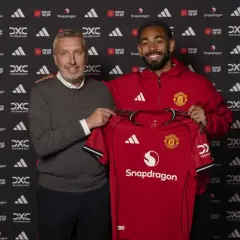 Dwóch mężczyzn prezentuje czerwoną koszulkę Manchester United. To kolejny z ekscytujących manchester united transfery.