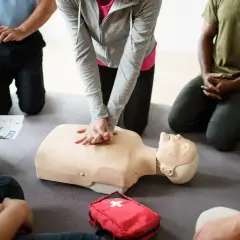 Persone in cerchio praticano RCP su un manichino. Si impara da chi sono designati gli addetti al primo soccorso.