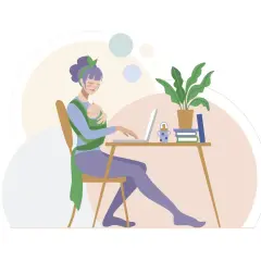 Kobieta z dzieckiem w chuście pracuje przy laptopie przy biurku.