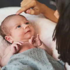 Delikatne dotknięcie palcem na zapadniętym ciemiączku noworodka. Mama czule bada główkę swojego dziecka.