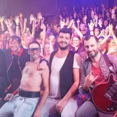La cover band dei Queen infiamma il pubblico con un'energia contagiosa. La folla alza le mani in segno di approvazione.