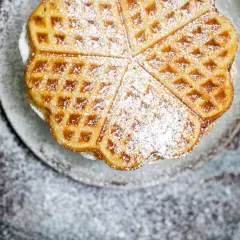 Herzförmige Waffeln, bestäubt mit Puderzucker, sehen aus wie aus einem perfekten Waffeln Rezept.