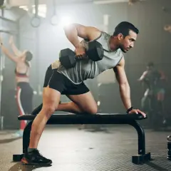 Mann mit shredded body trainiert im Fitnessstudio mit Hanteln.
