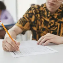 Uczeń pisze ołókiem na arkuszu testowym z wieloma polami wyboru.