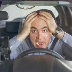 Uomo disperato al volante, mani sulla testa, con un'espressione di panico. Forse si può avere un'anomalia al differenziale.
