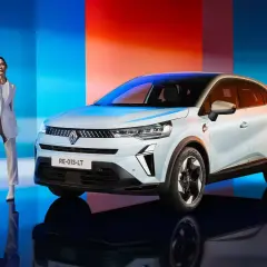 Eleganza e innovazione: una donna in tailleur bianco accanto alla nuova Captur GPL, con uno sfondo che sfuma dal blu al rosso.