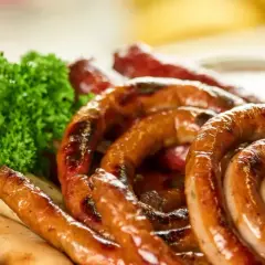 Talerz pełen grillowanych kiełbasek, w tym biała kiełbasa, z gałązkami natki. Idealna ilość soli do białej kiełbasy to klucz do smaku.