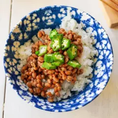 A bowl of natto with rice, topped with sliced okra. This healthy Japanese dish is ready to be enjoyed with chopsticks.