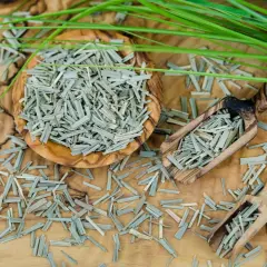 Getrocknetes Zitronengras in einer Holzschale und Schaufeln, bereit zur Zitronengras Zubereitung. Frische grüne Halme liegen daneben.