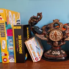 Brettspiele wie "Funkloch" und "30 Seconds" warten darauf, dass ihr Wort erraten wird. Ein Duden-Buch liegt daneben.