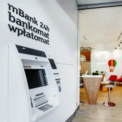 Wpłatomat mBank 24h, gotowy do obsługi o każdej porze. Wnętrze banku z nowoczesnym wystrojem.