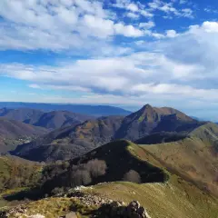 Panoramica mozzafiato del monte Matanna, con cime ondulate, boschi spogli e un cielo azzurro punteggiato di nuvole bianche.