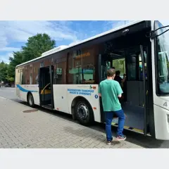 Autobus miejski z otwartymi drzwiami, wsiada pasażer.
