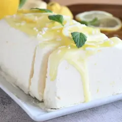 Un delizioso semifreddo al limone, guarnito con scorzette, menta e una glassa gialla. Perfetto per un dessert rinfrescante.