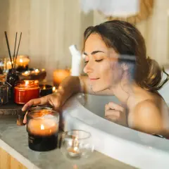 Entspannter beauty day zuhause: Frau genießt ein warmes Bad mit Kerzenlicht und duftenden Ölen.