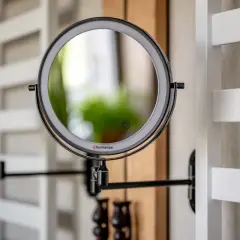 Eleganckie, czarne lustro łazienkowe z podświetleniem LED, zamontowane na wysięgniku. Obok widać drugie lustro.