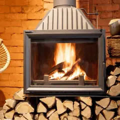 Le feu crépite dans la cheminée, mais la fumée refoule. Un fauteuil confortable et des bûches attendent.
