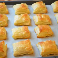 Upieczone kwadraty ciasta francuskiego na blasze. Czy ciasto francuskie można mrozić? Tak, można je zamrozić przed pieczeniem.