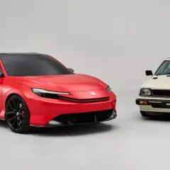 Nowy, czerwony koncept sportowego coupe obok klasycznego, kremowego Honda Prelude.