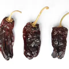 Tres pimientos choriceros secos, oscuros y arrugados, listos para dar sabor a guisos y salsas.