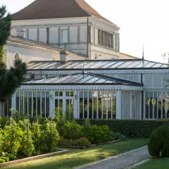 Jardin luxuriant devant une serre élégante, rappelant la beauté du caudalie vignoble.