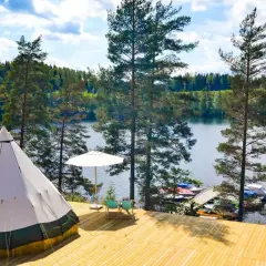 En stor tipi på en träaltan vid en sjö. Perfekt för natur camping med båtar vid bryggan.