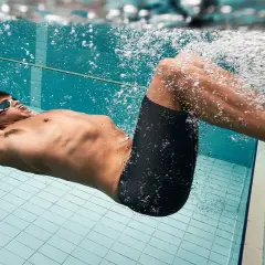 Schwimmer mit Brille und Badehose treibt unter Wasser. Das extensives intervalltraining fordert ihn.