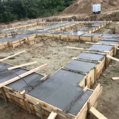Szalunki na fundamenty z wylanym betonem. Widać zbrojenie. To pierwszy krok, jak obliczyć beton na fundament.