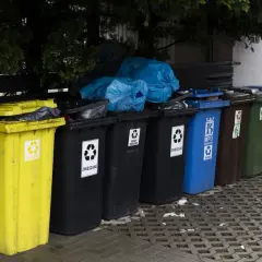 Różnokolorowe kosze na śmieci, w tym żółty na plastik, czarne na zmieszane, niebieski na papier. Zastanawiasz się, ile za śmieci w gminie?