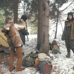 Zimowy obóz w lesie, namiot, ekwipunek i ludzie w strojach nawiązujących do bushcraftu. To właśnie bushcraft co to za przygoda!