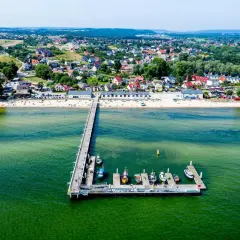 Mechelinki - warto jechać! Widok na molo, plażę i urokliwą nadmorską miejscowość.