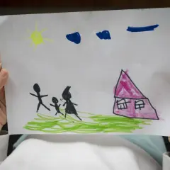 Disegni psicologia test bambini: una famiglia stilizzata cammina verso una casa rosa sotto un sole giallo e nuvole blu.