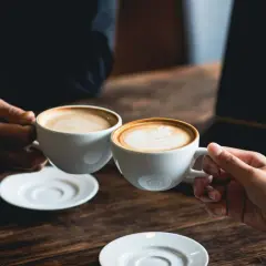 Dos tazas de café humeante, una con arte latte. El café es bueno para la concentración y el disfrute.