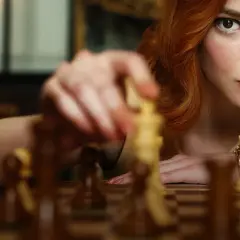 Anya Taylor-Joy jako Beth Harmon w "Gambicie Królowej" wykonuje ruch figurą na szachownicy.