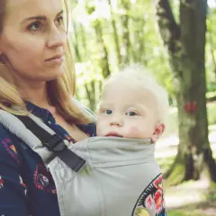 Mama z dzieckiem w nosidle w lesie. Zastanawiasz się, jakie nosidełko wybrać? To wygodne rozwiązanie na spacery.